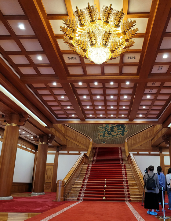 Visitors entering into the Main Office Building can see the red-carpeted staircase and a grand chandelier. The painting at the back of the stairs is Kim Sik's "Geumsugangsan (The Beautiful Land of Korea)" (1991). [MOON SO-YOUNG]