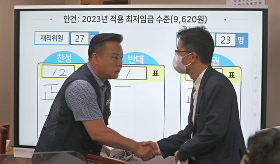 Minimum Wage Commission Chairman Park Joon-shik, right, and Lee Dong-ho, a general secretary at the Federation of Korean Trade Unions, shake hands following a meeting held at the government complex in Sejong early Thursday. [NEWS1]