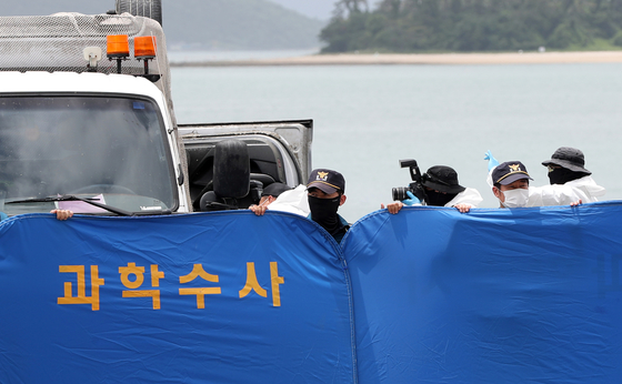 Police take photographs of the overturned vehicle belonging to the family of 10-year-old schoolgirl Cho Yoo-na behind a blue forensic investigation screen in Wando, South Jeolla on Wednesday. [YONHAP]