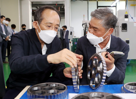 Finance Minister Choo Kyung-ho looks at a metalic part for export at a company in Incheon on Friday. [YONHAP] 