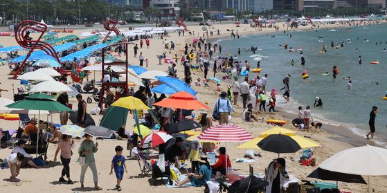 Beach-goers cool themselves at Haeundae Beach in Busan Sunday as a heat wave provides an intermission to the rainy season. The Korea Meteorological Administration issued its first heat wave alert Saturday, 18 days earlier than last year. As Typhoon Aere approaches Jeju Island, strong winds and torrential rainfall are expected on Monday and Tuesday. The weather agency forecast that Typhoon Aere will approach 220 kilometers south of Seogwipo, Jeju Island, on Monday afternoon and then move toward Japan on Tuesday morning.   [SONG BONG-GEUN]