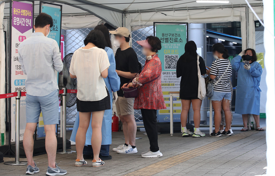People line up at a Covid-19 testing center in Yongsan District, central Seoul, on Sunday, as cases again passed 10,000. [NEWS1]