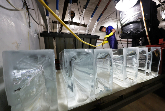 An employee at Daewon Cold Storage Industrial, which specializes in industrial-sized refrigerators, works on ice blocks in Bucheon, Gyeonggi, on Monday. The temperature outside has been rising, and the average midday temperature in Seoul on Sunday exceeded 35 degree Celsius (95 degrees Fahrenheit). [YONHAP] 
