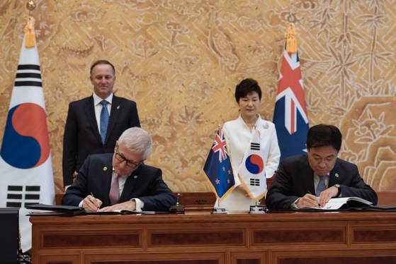 New Zealand Prime Minister John Key, left, with Korea's President Park Geun-hye, right, preside over the signing of the bilateral free trade agreement in Seoul on March 23, 2015. [BLUE HOUSE]