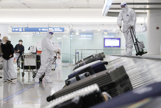Staff disinfect luggage at Terminal 1 of Incheon International Airport. [YONHAP] 