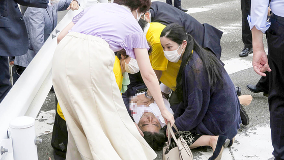 Japan’s former Prime Minister Shinzo Abe, center, falls on the ground in Nara, western Japan on Friday. Abe was in heart failure after apparently being shot during a campaign speech Friday in western Japan, NHK reported. [AP/YONHAP] 