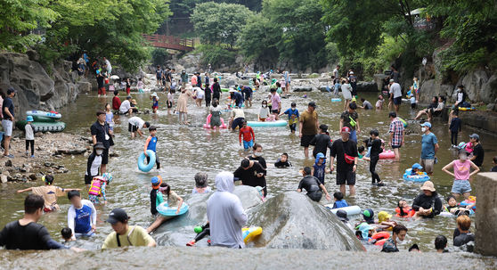 People cool off in water in a valley in Gwangju, Gyeonggi, on Sunday as temperatures continue to soar.  [YONHAP]