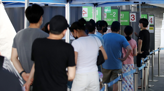 People stand in a line at a Covid-19 screening clinic at the Yongsan District Public Health Center in central Seoul on Sunday morning. [NEWS1]