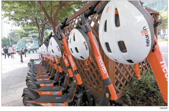 Electric scooters are lined in front of a subway station in Gangnam District, southern Seoul, in 2021. Under a revised law, any one who rides an e-scooter without wearing a helmet is fined 20,000 won ($15). [YONHAP]