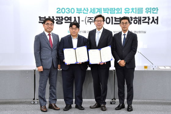 Busan Mayor Park Heong-joon, second from right, and HYBE Chairman Bang Si-hyuk, second from left, pose with an agreement on June 24 where the popular boy band BTS will be holding a concert in the city in October in support of Busan’s bid to host the World Expo in 2030. [BUSAN METROPOLITAN CITY GOVERNMENT]