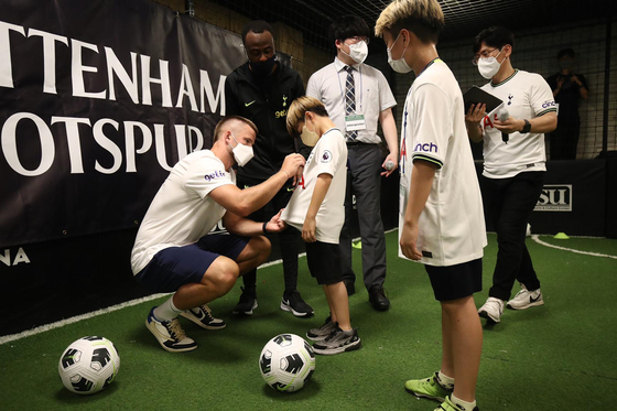 Eric Dier, left, signs a young fan's shirt during a Tottenham Hotspur Global football development session with children from ChildFund Korea on Monday in Yangcheon District, western Seoul. [TOTTENHAM HOTSPUR]