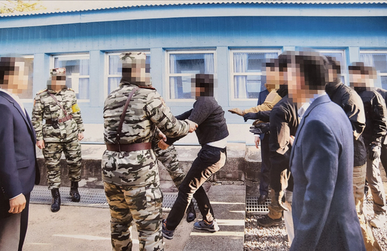 Another photograph released by the Unification Ministry on Tuesday shows one of the fishermen being dragged across the border into the North by North Korean soldiers. [UNIFICATION MINISTRY]