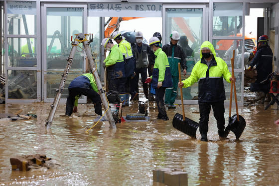 Workers clean the tracks and platform of the KTX at Gwangmyeong Station in Gyeonggi, which was flooded by muddy water after torrential rain in the area on Wednesday. [YONHAP]