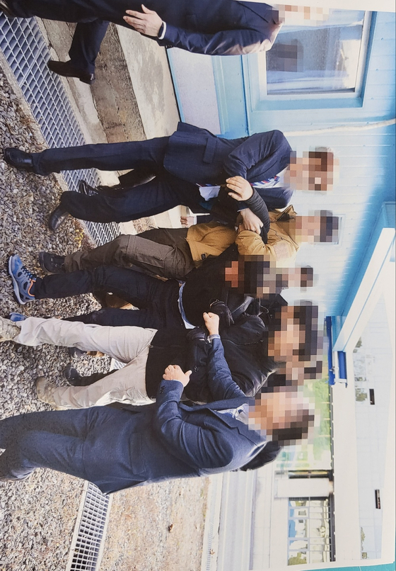 In this photo released by Seoul's Unification Ministry on Tuesday, one of two North Korean fishermen repatriated by South Korea in November 2019 is seen being half-carried by South Korean officials toward the Military Demarcation Line in the truce village of Panmunjom on the inter-Korean border. [UNIFICATION MINISTRY] 