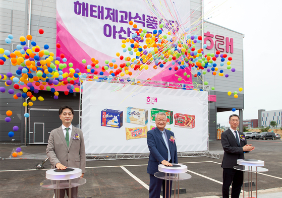 From left: Shin Jung-hoon, CEO of Haitai Confectionery & Foods, Yoon Young-dal, CEO of Crown-Haitai, and Yoon Seok-bin, CEO of Crown Haitai Holdings, pose for a photo while celebrating the opening of the Asan plant on Tuesday. [HAITAI CONFECTIONERY & FOODS] 