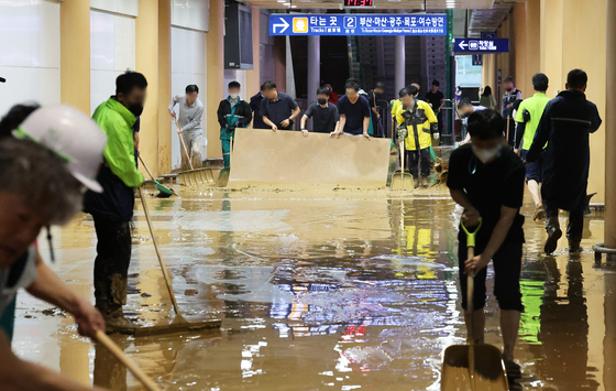 Workers clean up the KTX Gwangmyeong Station Wednesday afternoon as the station was flooded after heavy rain. [YONHAP]