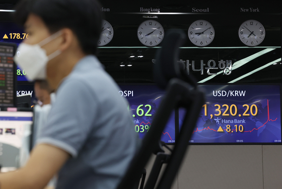 An electronic display board, right, shows the won against the dollar at a dealing room in Hana Bank in central Seoul on Friday [YONHAP]