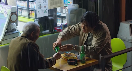 In a scene from Netflix's ″Squid Game″ (2021), Il-nam and Gi-hun share soju with each other in front of a table set up at a convenience store. [SCREEN CAPTURE]