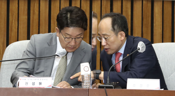 People Power Party's floor leader Kweon Seong-dong, left, and Finance Minister Choo Kyung-ho during a meeting on Monday at the National Assembly in Seoul. [JOINT PRESS CORPS] 
