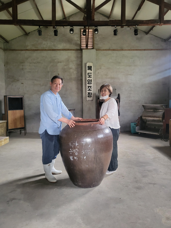 Lee Suk-yl, left, and Yoo Gi-ok, owners of Mokdo Brewery in Goesan, North Chungcheong, pose for a photo with one of the earthen jars used decades ago to make makgeolli, fermented rice wine. Many of the unused tools and equipment are displayed at the brewery so that visitors can learn about the transformation of Korea's makgeolli (traditional Korean rice wine)-making tradition. [YIM SEUNG-HYE] 