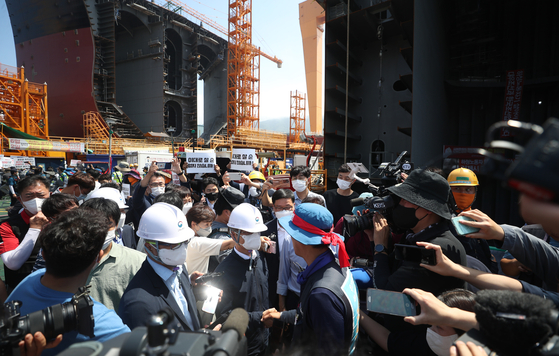 Wearing a hard hat, Employment and Labor Minister Lee Jung-sik, second from left, shakes hands with Kim Hyung-soo, regional head of the Korean Metal Workers’ Union of shipbuilding subcontractors, at Daewoo Shipbuilding and Marine Engineering’s Okpo shipyard in Geoje, South Gyeongsang, on Tuesday. The government requested that the union ends its strike, and President Yoon Suk-yeol on the same day told reporters that the Korean people have waited long enough. The losses generated from the ongoing strike, which reached its 47th day Tuesday, is estimated at 570 billion won ($435 million). [YONHAP]