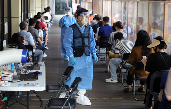 Medical workers help people line up for virus tests at a screening center in Songpa District, southern Seoul, on Tuesday. [NEWS1]