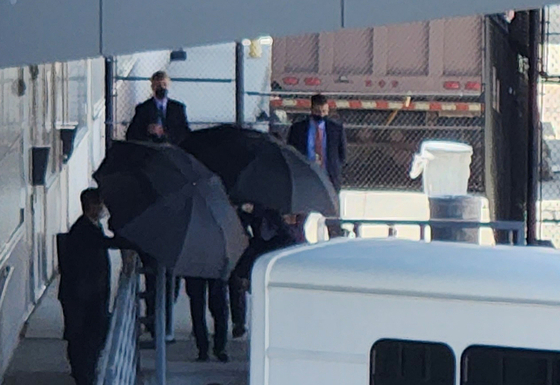 National Intelligence Service Director Kim Kyou-hyun walks out of Washington's Dulles Airport on Tuesday as aides try to shield him from public view with umbrellas. [YONHAP] 