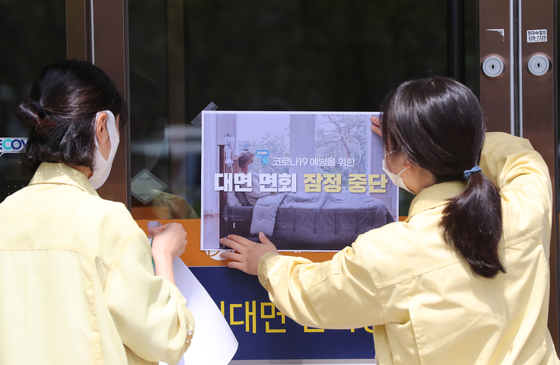 Workers put up a notice of a suspension of face-to-face meetings at a nursing home in Gwangju on Wednesday amid the resurgence of Covid-19. [YONHAP]