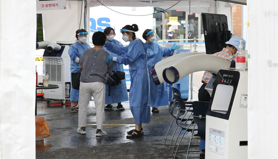 Health workers give directions to people wanting to get tested for Covid-19 at a testing center in Gangnam, southern Seoul, on Thursday. [YONHAP]