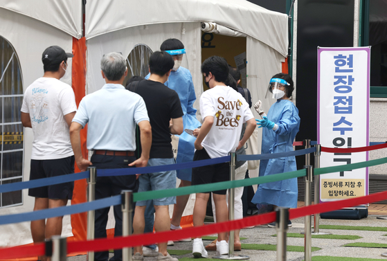 People wait in line to get tested for Covid-19 at a testing center in Gangnam District, southern Seoul, Friday. [YONHAP]