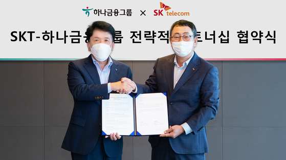Hana Financial Group Chairman Ham Young-joo, left, and SK Telecom CEO Ryu Young-sang poses with agreements on swapping shares at SK Telecom’s headquarters in Euljiro, Seoul, on Friday. [HANA FINANCIAL GROUP, SK TELECOM]