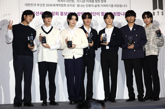 BTS members pose in front of cameras after being appointed as ambassadors for Busan’s bid to host the 2030 World Expo last Tuesday at their agency HYBE in Yongsan District, central Seoul. [YONHAP]