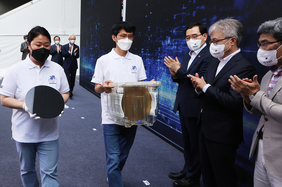 Samsung Electronics employees carry wafers manufactured with 3-nanometer technology on Monday during a shipping ceremony for the products at the chipmaker's plant in Hwaseong, Gyeonggi. Samsung Electronics became the world's first company to mass produce 3-nanometer chips. [NEWS1]