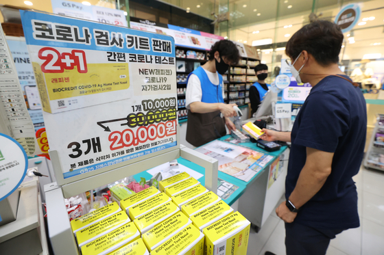 A customer buys a self-testing kit at a GS25 convenience store in Seoul, Monday, as the store runs a buy-two-get-one-free event amid a resurgence in Covid-19 cases. [YONHAP]
