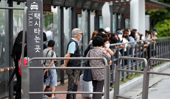 People line up for cabs at the Express Bus Terminal in Seocho District, southern Seoul, on Thursday. Demand for taxis has increased drastically since the end of social distancing measures, creating a shortage. [NEWS1]