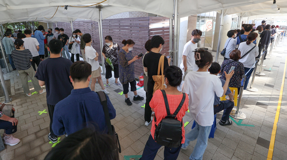 People wait in line to get tested for Covid-19 at a testing center in Mapo District, western Seoul, Monday. [YONHAP]