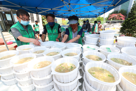 Community center workers in Dong District in Daegu prepare to deliver samgyetang (Korean ginseng chicken soup) for jungbok, the beginning of the second phase of the midsummer heat, on Tuesday. Workers delivered the food to elderly people living alone and low income earners in the area. [YONHAP]