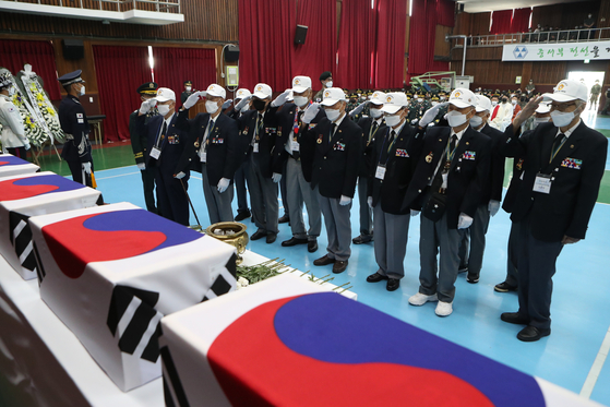 Korean War veterans salute coffins bearing the remains of fellow soldiers at a joint funeral ceremony held by the sixth corps of the Army in Pocheon, Gyeonggi, on Tuesday. The sixth corps recovered the remains of 21 soldiers from the Mount Jinmyeong area in Yeoncheon County, Gyeonggi, from April to May. [YONHAP]