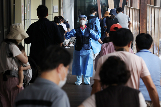A health worker guides people waiting to get tested for Covid-19 at a testing center in Songpa District, western Seoul, Wednesday. [NEWS1]
