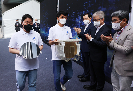Samsung Electronics employees carry wafers manufactured with 3-nanometer technology on July 25 during a shipping ceremony for the products at the chipmaker's plant in Hwaseong, Gyeonggi. Samsung Electronics became the world's first company to mass produce 3-nanometer chips. [YONHAP]
