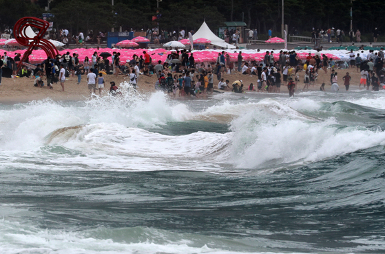 Beachgoers are not allowed to go into the water at Haeundae Beach in Busan on Sunday as Typhoon Songda, which is moving toward the Yellow Sea between China and Korean Peninsula, creates dangerous rolling waves. Typhoon Songda will dissipate Monday afternoon after bringing heavy rainfall to the country. [YONHAP]