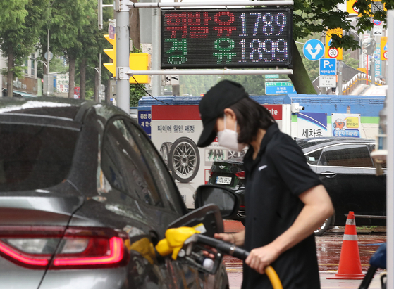 An attendant at a station in Gangseo District, western Seoul, pumps gas on Sunday. The digital sign board reads that gasoline is sold at 1,789 won ($1.37) won per liter and diesel at 1,899 won per liter. Gas prices have falled for the fourth straight week amid lowering crude oil prices and tax cuts. [NEWS1]