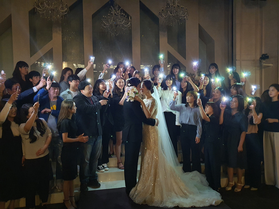 Volleyball player Hwang Youn-joo and basketball player Park Gyeong-sang pose for a classic wedding photo with their friends during their ceremony in a hotel in Seoul on May 16, 2020. [HYUNDAI E&C]