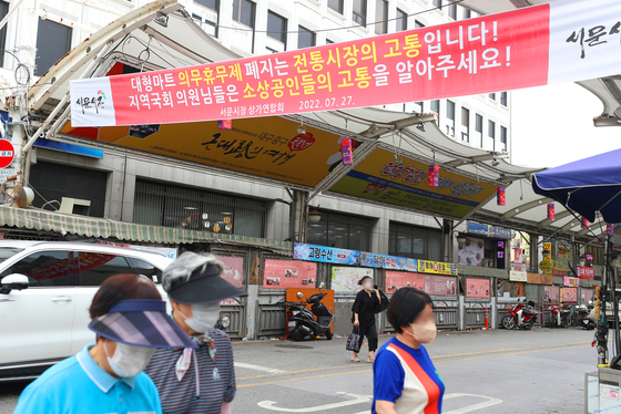 A banner seen on Monday at the Seomun Market in Daegu says the abolition of compulsory closures of large discount marts is a threat to the traditional market. [YONHAP] 