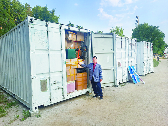 Pastor Won Seung-jae stands in front of containers with donations collected for the people of Haiti at the Busan Samsung Girls' High School in Busan. [JOONGANG ILBO]