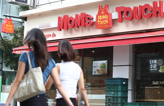 People pass by Mom’s Touch, a chicken burger franchise, in Seoul on Tuesday. The Korean franchise announced that it will be raising the price of 50 items on its menu starting Thursday. The price hike comes just six months after the franchise raised the price of 37 items in February. The price of its signature Thigh Burger will be raised from 4,100 won ($3.1) to 4,300 won. According to Statistics Korea, last month, the cost of dining out rose 8.4 percent, a 30-year high. [YONHAP] 