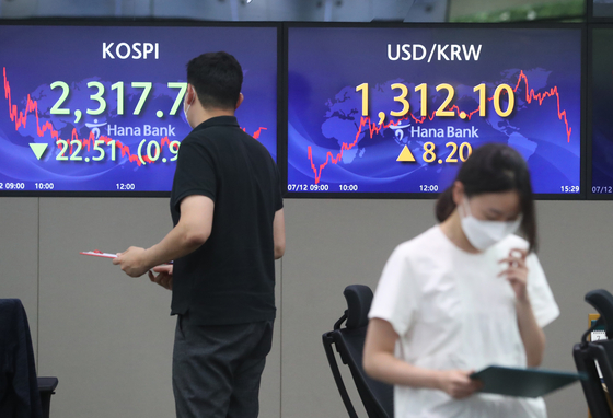 An electronic display board, right, shows the won against the dollar at a dealing room in Hana Bank in central Seoul on Tuesday. [NEWS1]