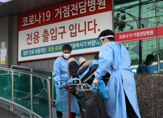 Paramedics bring a Covid-19 patient into a hospital in Gwangjin District, eastern Seoul on Wednesday afternoon. [NEWS1] 
