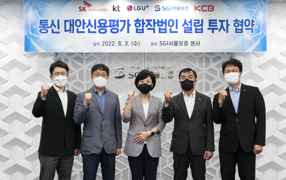 Representatives from KT, SK Telecom, LG U+, Korea Credit Bureau, and Seoul Guarantee Insurance (SGI) pose for a photo during a signing ceremony to establish a joint venture on Wednesday at SGI headquarters in Jongno District, central Seoul. [SK TELECOM]