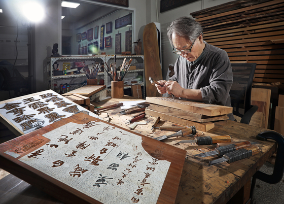 Kim demonstrates how he engraves letters on a woodblock at his studio. [PARK SANG-MOON]